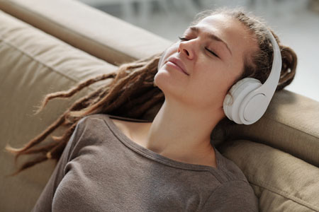 Relaxed girl with headphones smiling while listening to calming music on couch